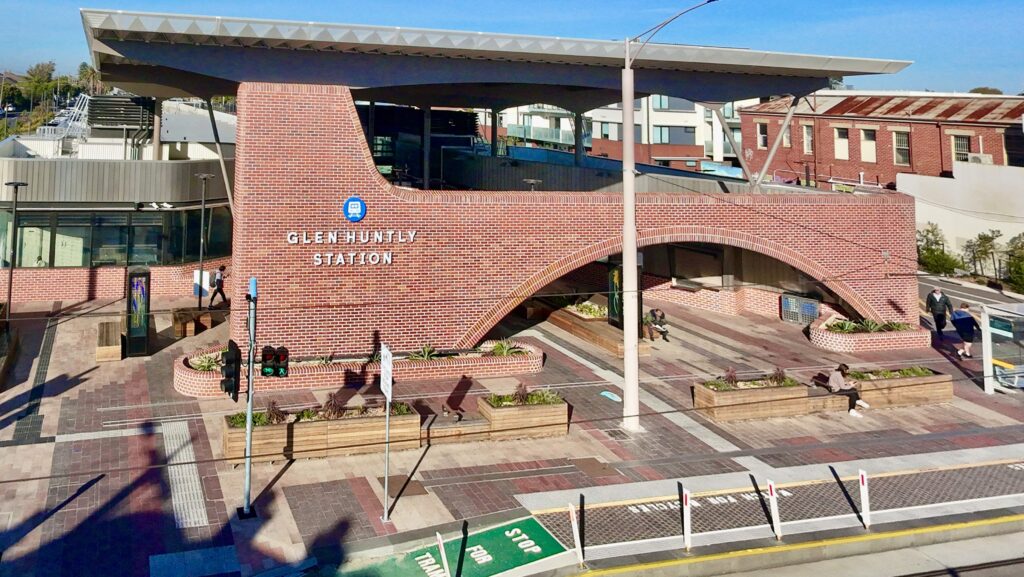 An elevated view of the architecturally striking Glen Huntly Station, showcasing its grand brick arches and the patterned stone forecourt supplied by Eigen Stones.