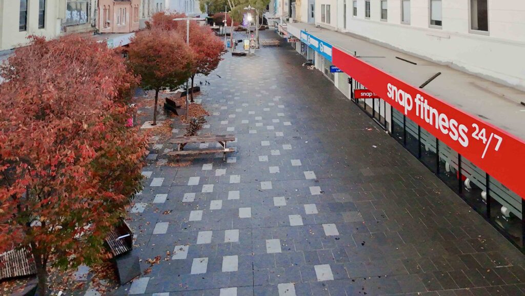 An aerial view looking down the Nicholson Street Mall in Footscray, showing the patterned stone paving from Eigen Stones between rows of autumn trees.