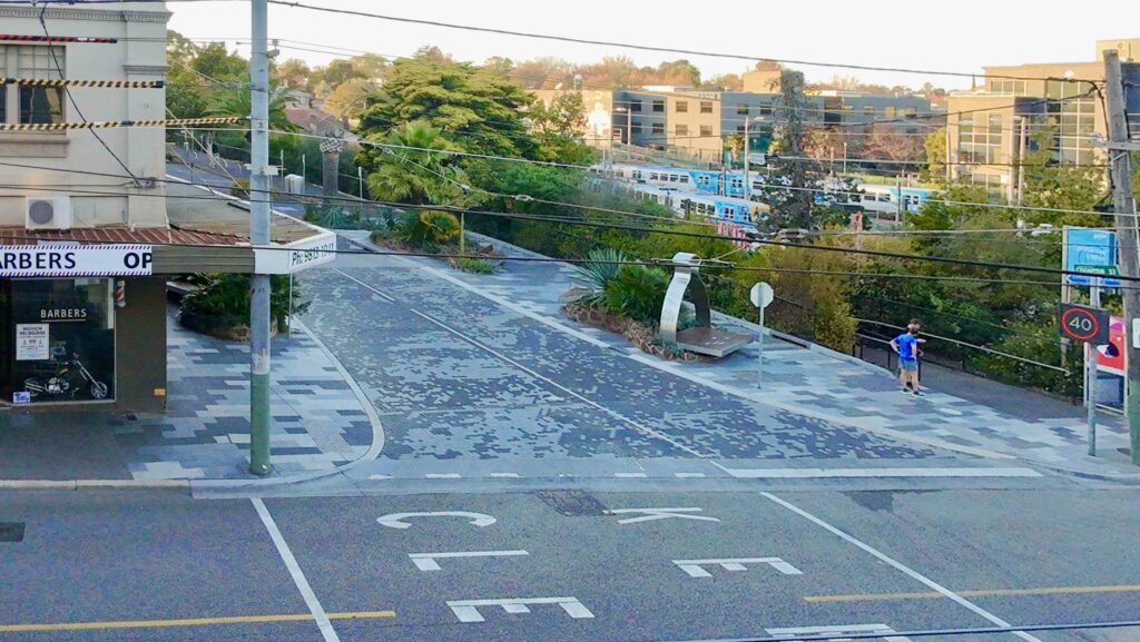 An aerial view of the sprawling RMIT Bundoora campus, showing a long, winding stone pathway from Eigen Stones connecting buildings through a native, tree-filled landscape.