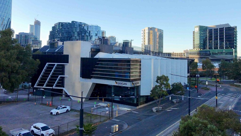 An elevated view of the stone-paved St Mary of the Cross Square at ACU, with autumn trees casting long shadows, featuring materials from Eigen Stones