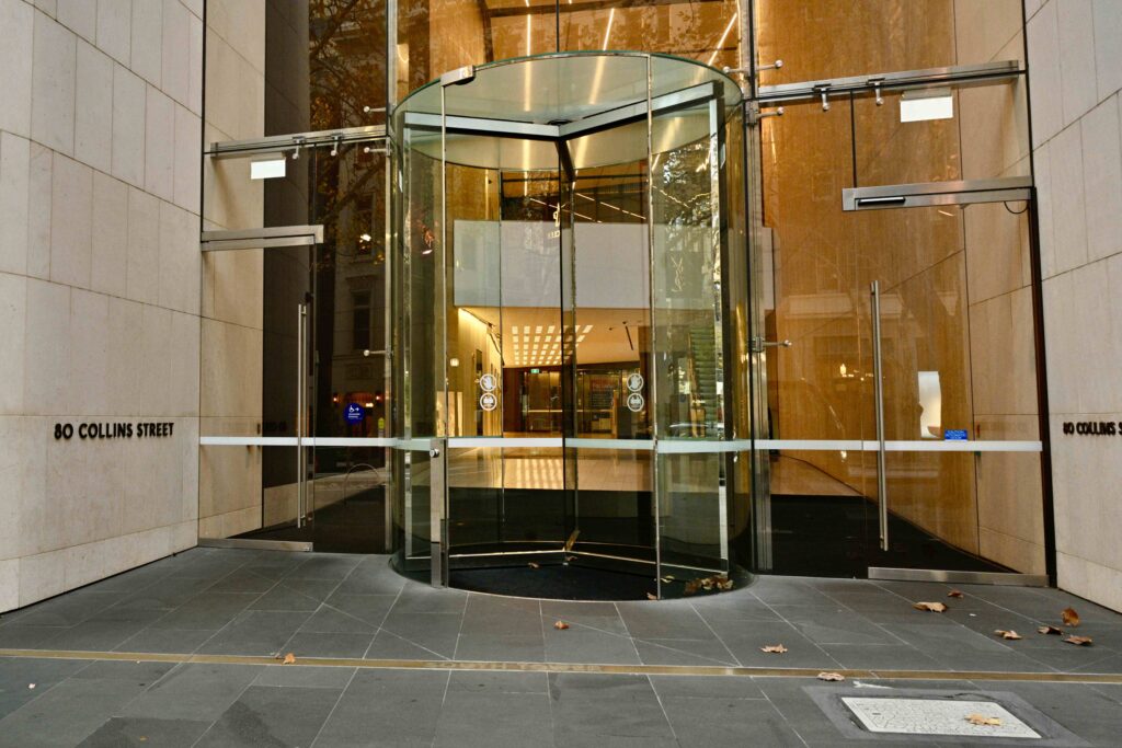 The prestigious entrance to 80 Collins Street, featuring a modern revolving glass door set within a forecourt of elegant, dark stone pavers supplied by Eigen Stones.