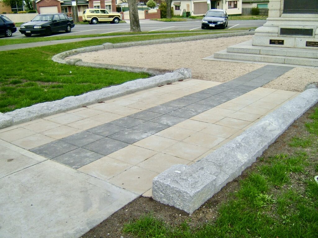 The paved memorial path at Sunbury, showing the light and dark stone pavers and the rustic stone kerb supplied by Eigen Stones.