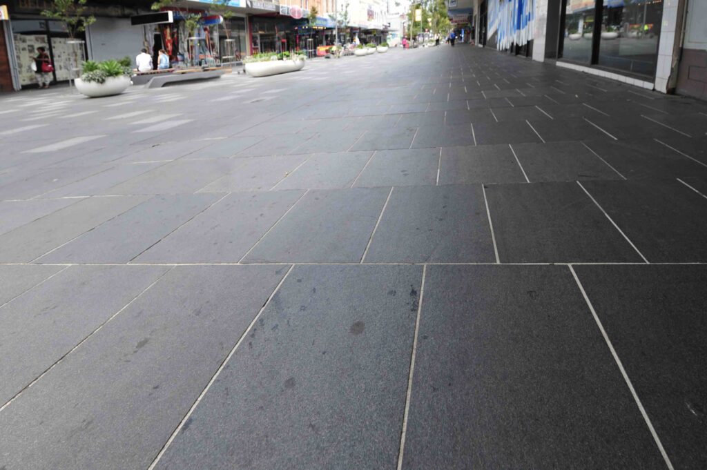 A low-angle, perspective shot of the dark, large-format stone pavers from Eigen Stones, creating a clean and expansive walkway in the Nicholson Street Mall.