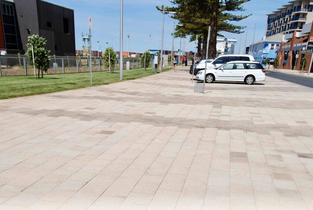 A wide view of the Bernie Waters coastal plaza, paved with large-format, light-toned stone pavers in a subtle pattern, supplied by Eigen Stones.