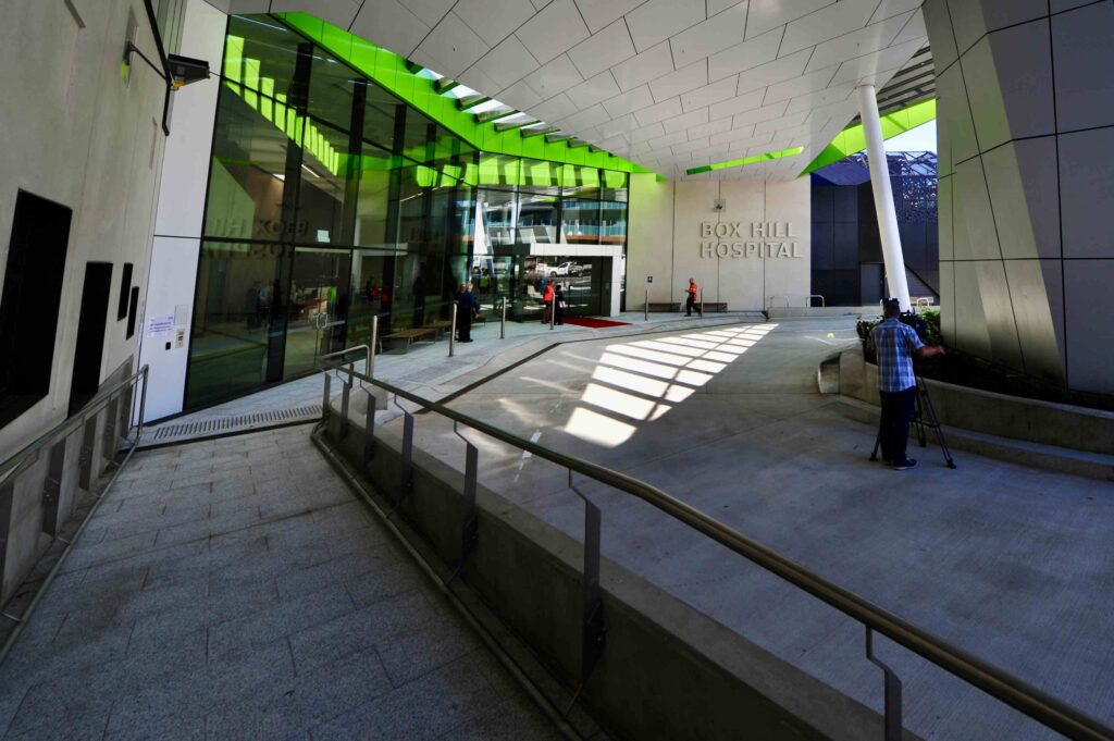 The dramatic, architecturally designed entrance canopy of Box Hill Hospital, sheltering a wide, accessible stone-paved area supplied by Eigen Stones.