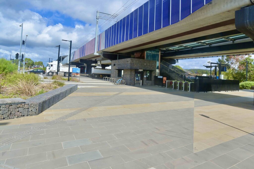 The entrance gates to Mernda Station, set within a plaza of multi-toned stone pavers that create a striped effect, supplied by Eigen Stones.