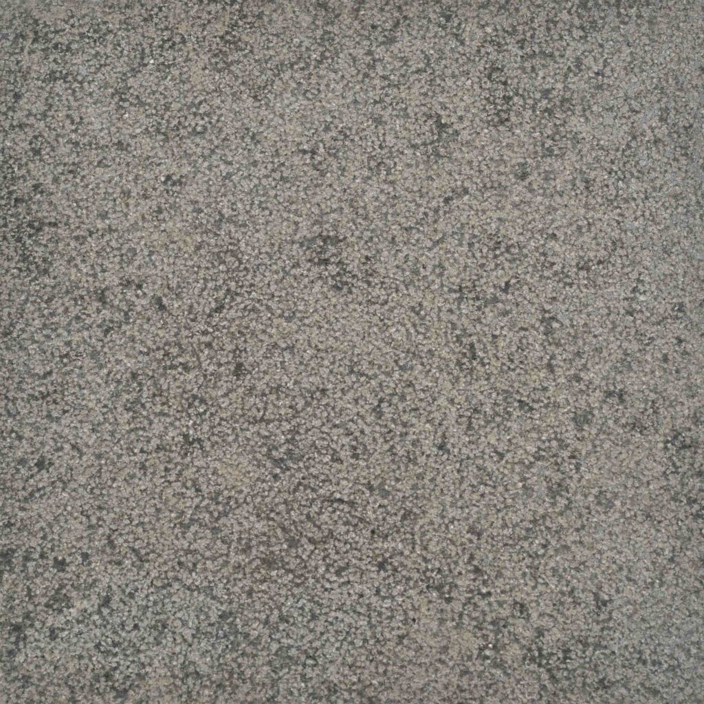 Raven_BH.jpg: A detailed macro photograph of the Raven Bush Hammered stone paver, showcasing its fine, sandy texture and warm, earthy grey-tan colour palette.