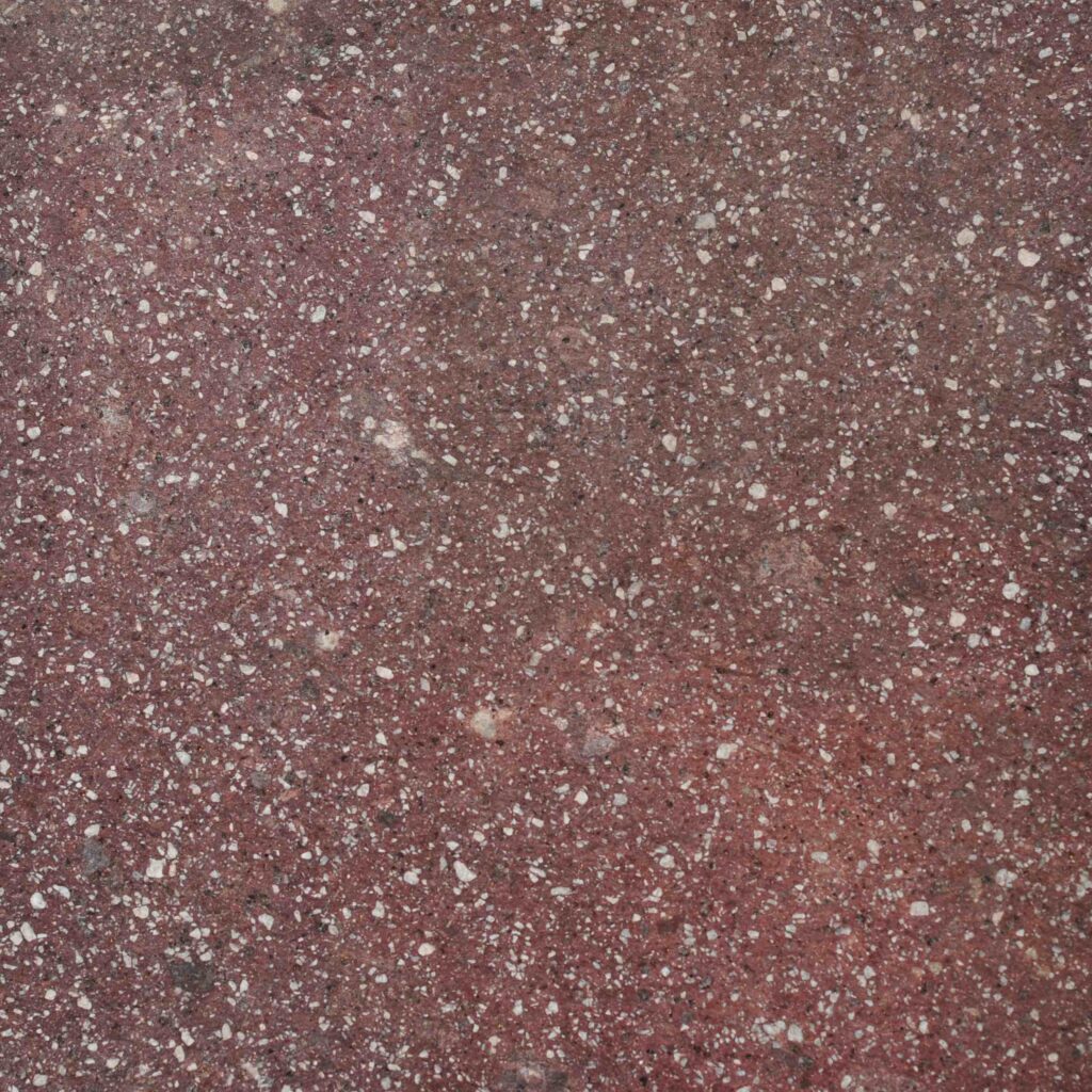 Red_Bear_Exfoliated.jpg: A detailed macro photograph of the Red Bear Flamed (Exfoliated) stone paver, showcasing its dramatic, deep red and burgundy tones speckled with crystalline flecks.