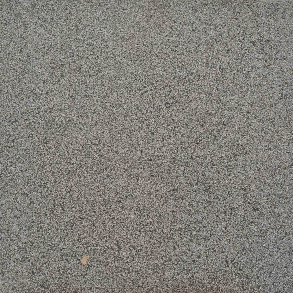 Takhi_BH.jpg: A detailed macro photograph of the Takhi Black Bush Hammered stone paver, showcasing its deep, consistent colour and fine, sparkling surface texture.